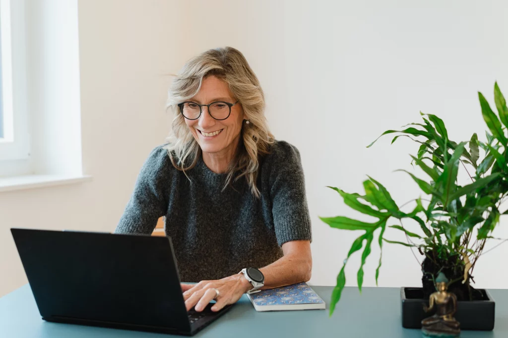 Katja Hartmann sitzt an einem Schreibtisch vor einem Laptop und hat ein Online-Mentoring