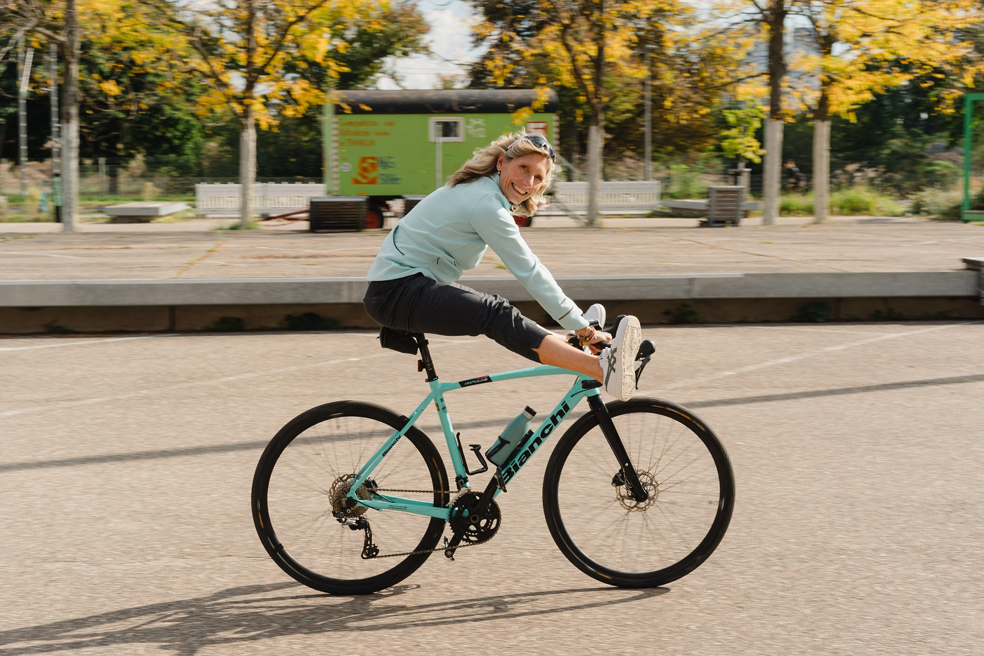 Katja Hartmann sitzt auf einem Fahrrad, die Beine nach oben bis ans Lenkrad und lacht in die Kamera
